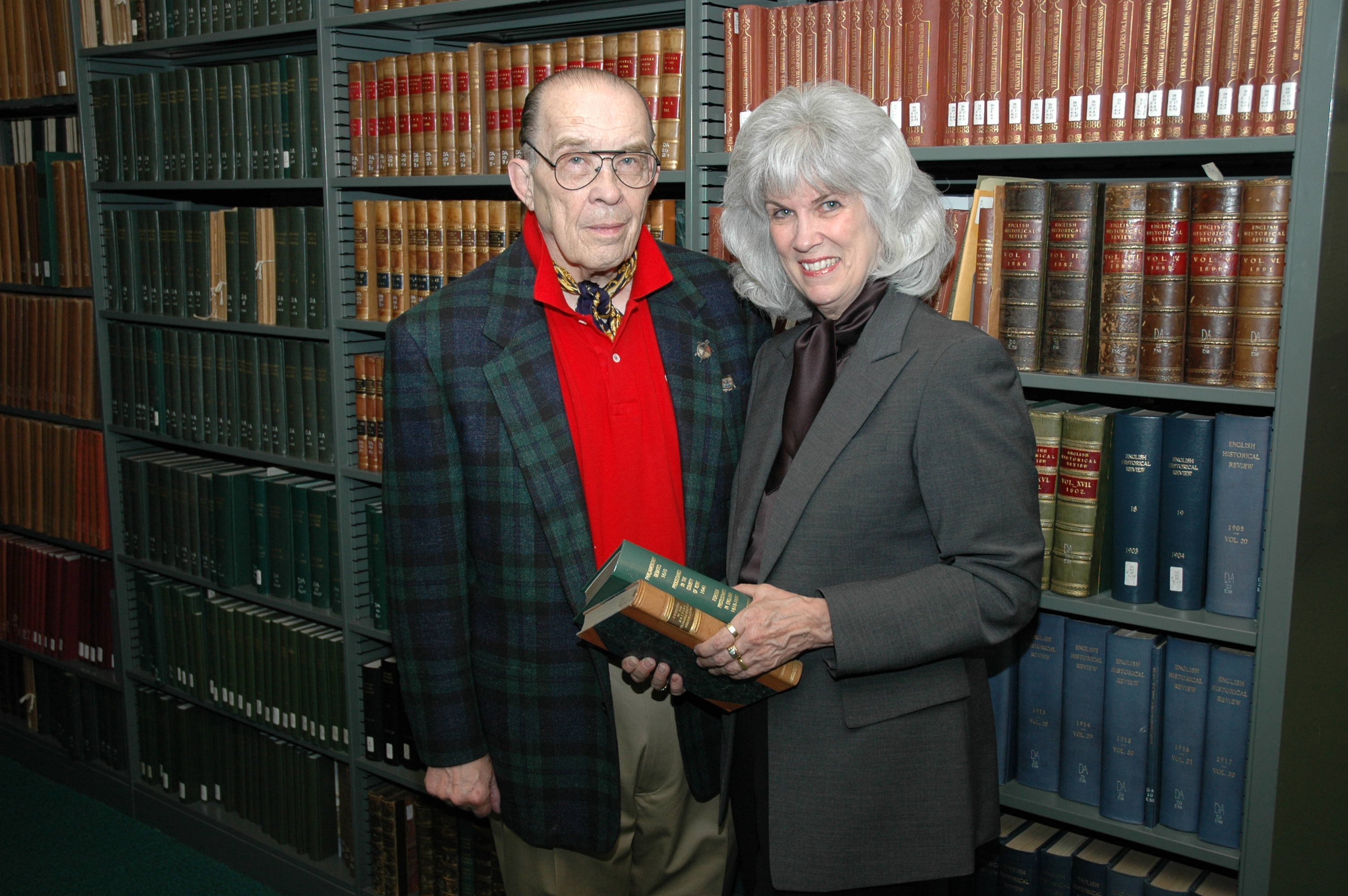 Two people stand in a library.