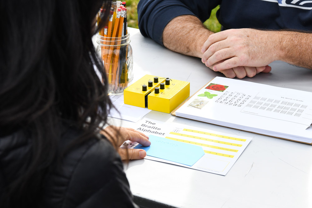 Overhead view of a table with two people reading Braille.