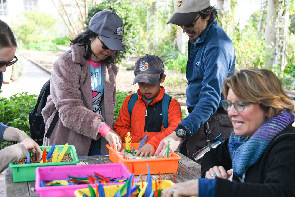 People surround a table covered in craft supplies.