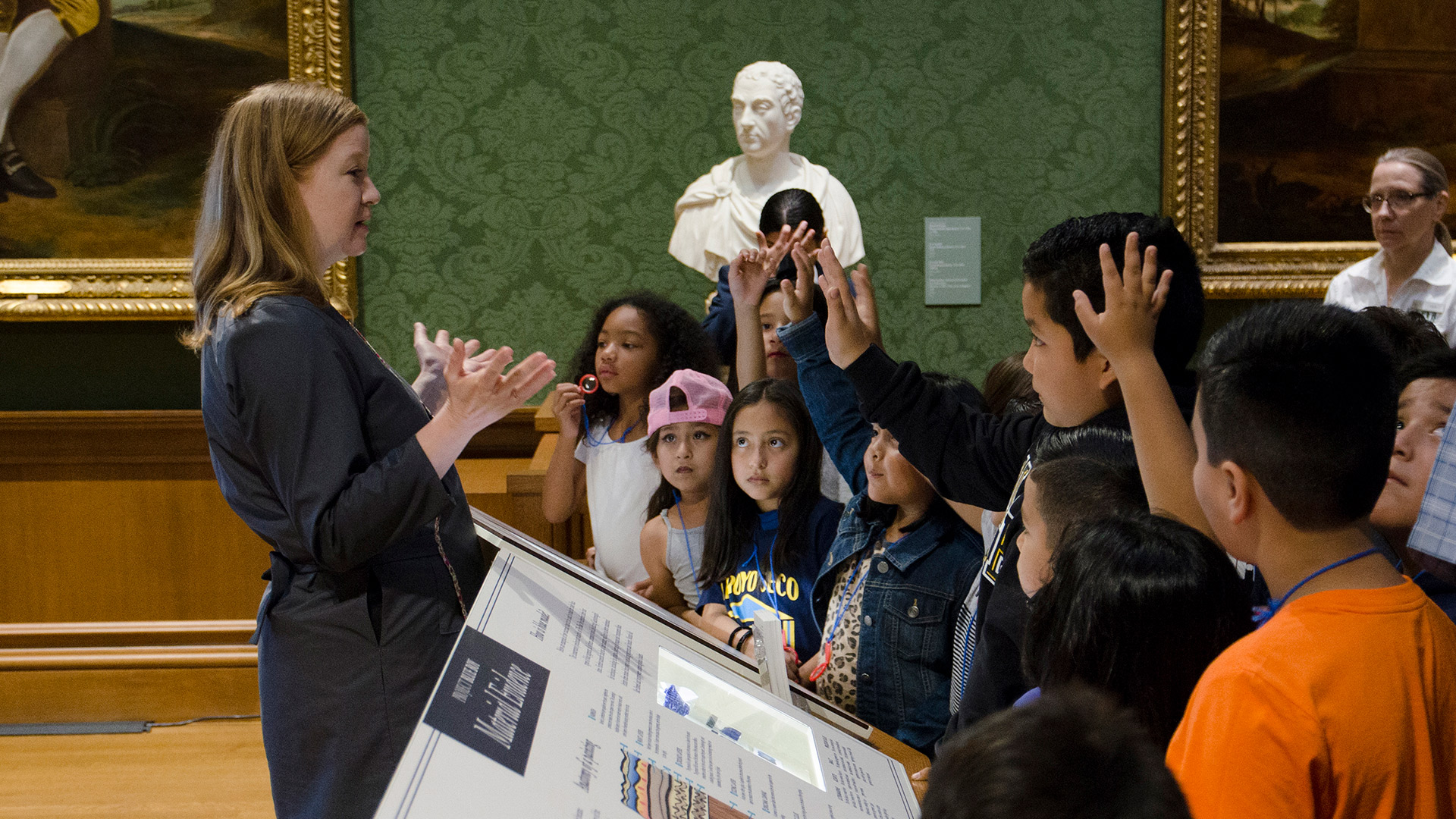 children in gallery raising hands