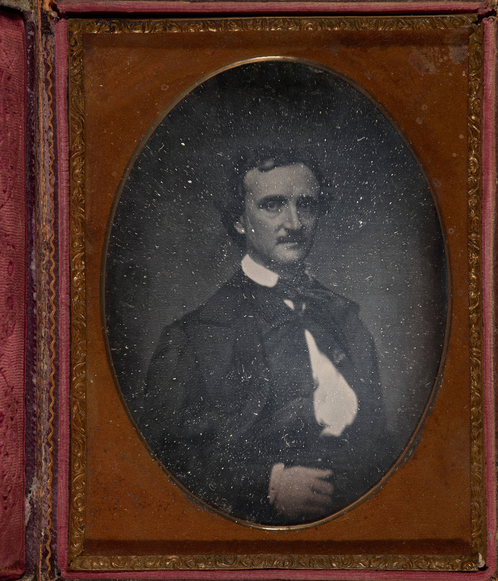 A golden-brown frame with red velvet accents surrounds an oval portrait of a seated man in a suit and tie.