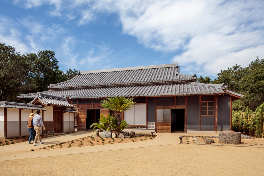 A traditional Japanese home with a gravel courtyard on a sunny day.