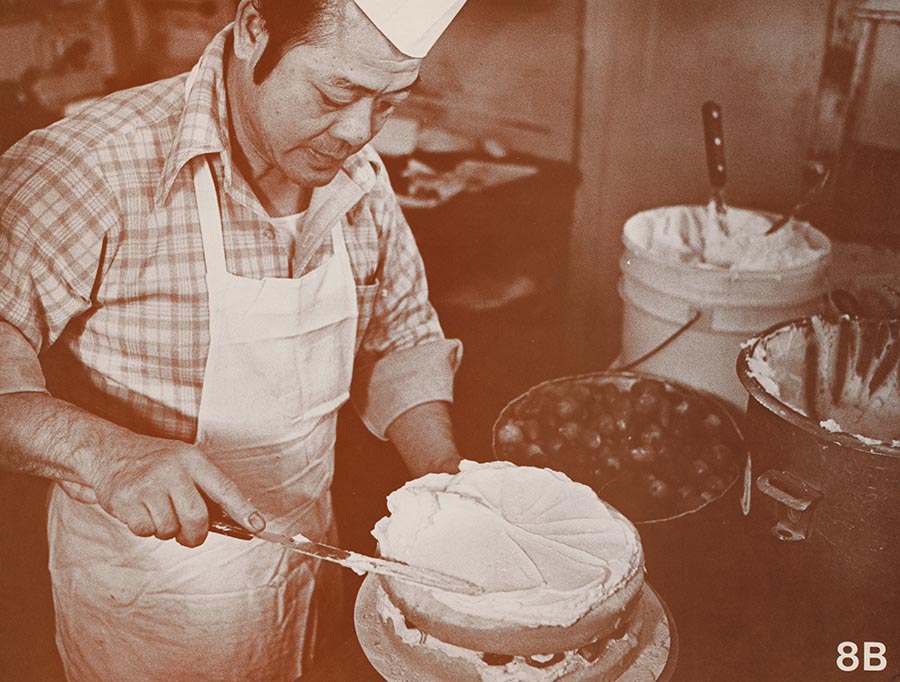 Man adds frosting to a cake.