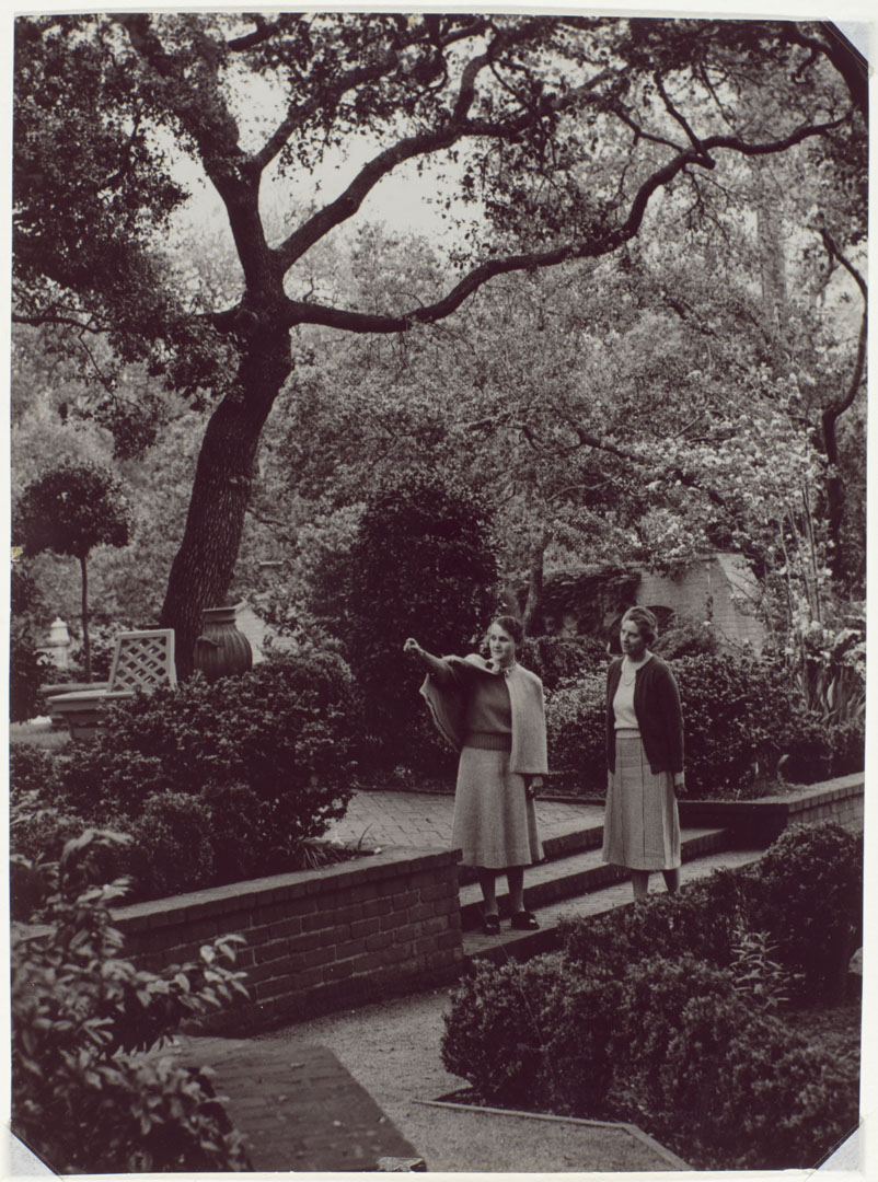 A black-and-white photograph of two people in a garden.