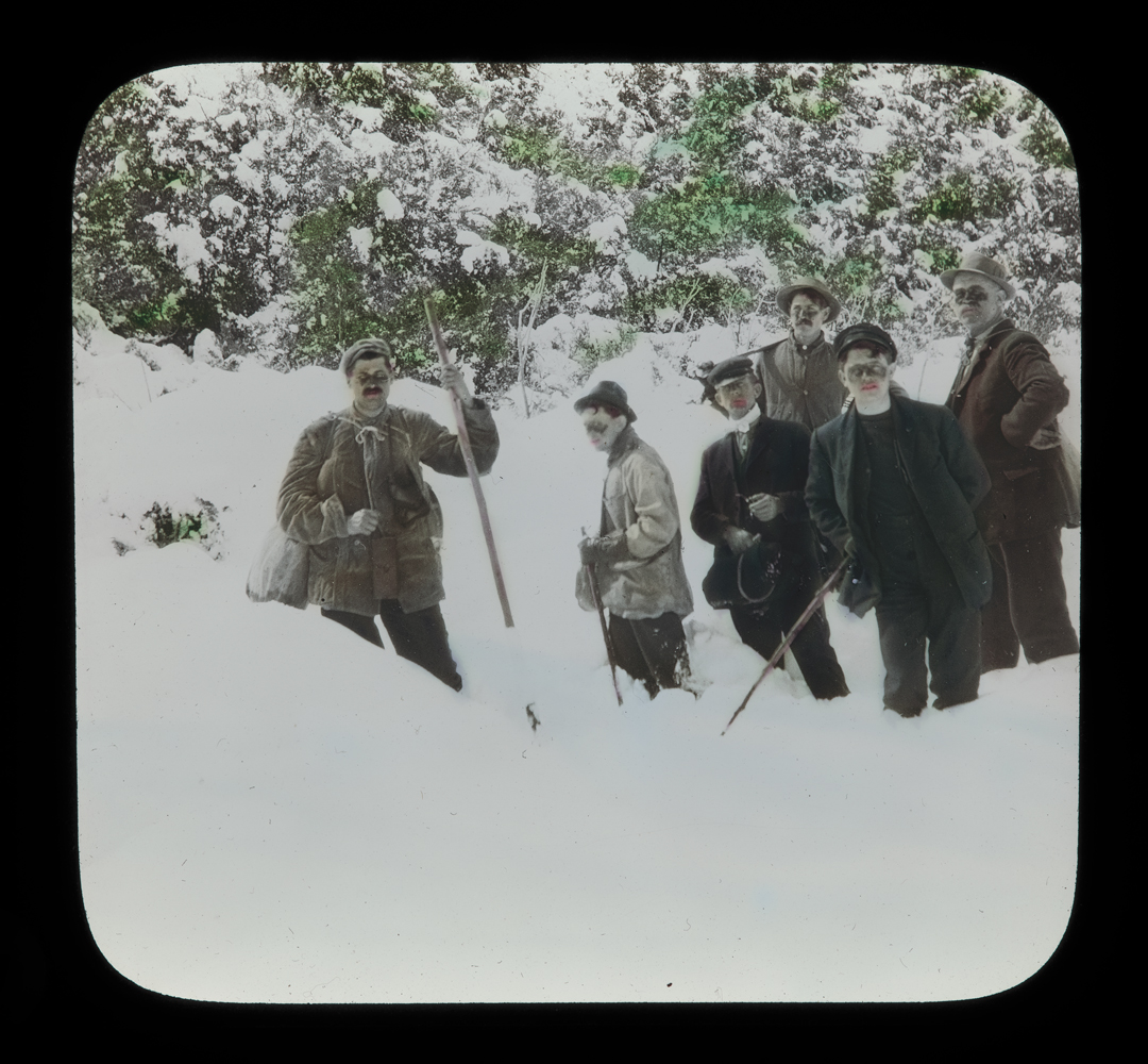 A group of people stand in a deep snow.