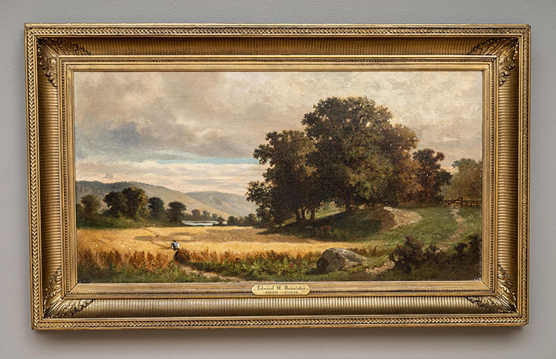 Painting of a person walking through a field of wheat with oak trees on a nearby hill.