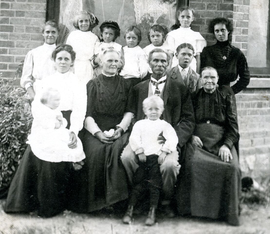 A black and white family portrait taken outdoors in front of a house.