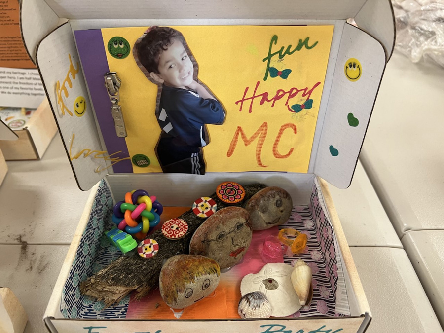 A box filled with various found objects, patterned papers, and a photo of a child.