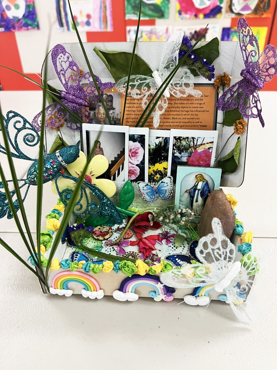 A box filled with various found objects, plant material, decorative butterflies, and photos.