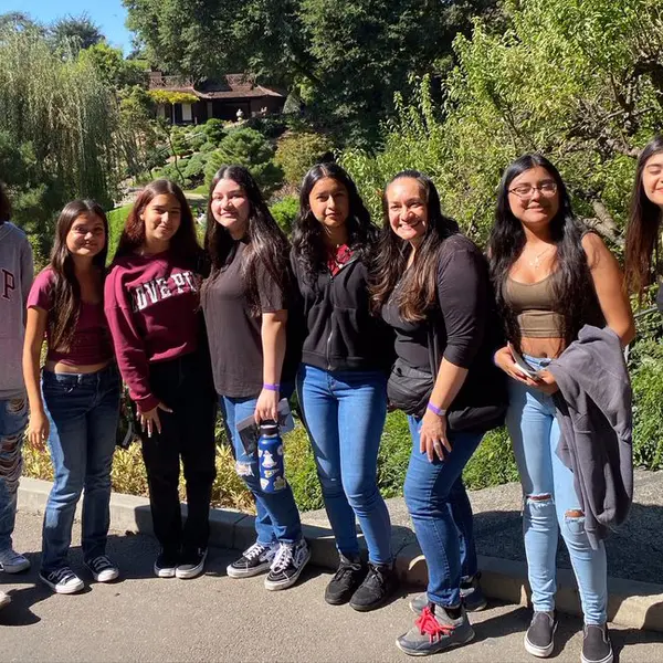 Students pose for a group photo outside in a garden.