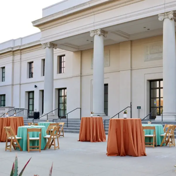 A courtyard filled with party tables covered in teal blue and darker peach tableclothes.