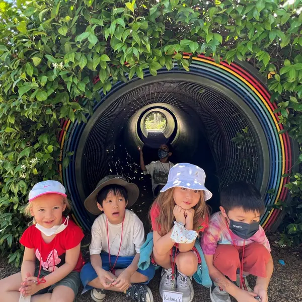 young kids sitting by garden rainbow tunnel