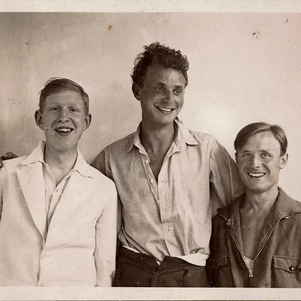 Black-and-white photo of three young men smiling.