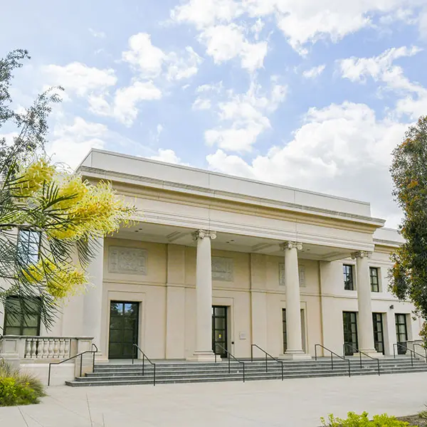 A two-story building with a four-column portico and a staircase.