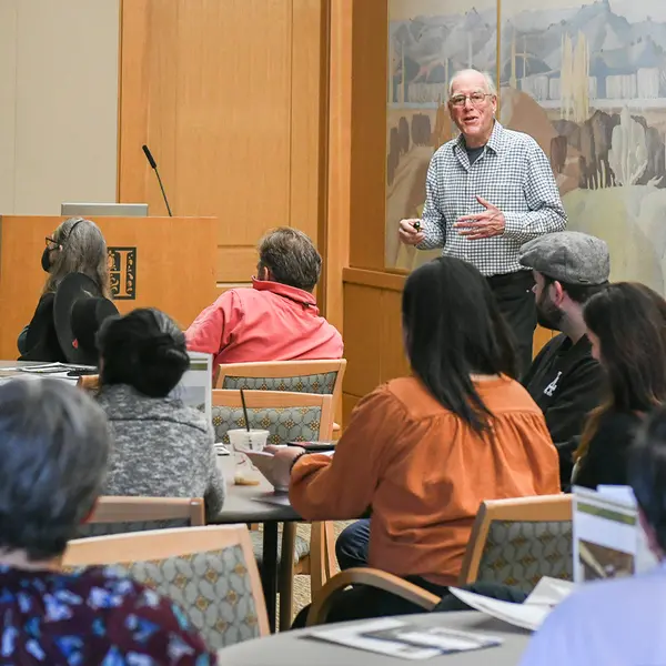 A person stands in front of a seated audience.