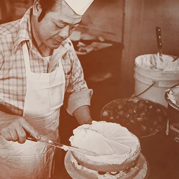 Man adds frosting to a cake.