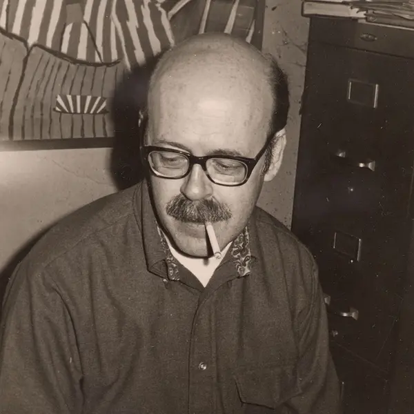 Black-and-white photo of person typing with cigarette in mouth.