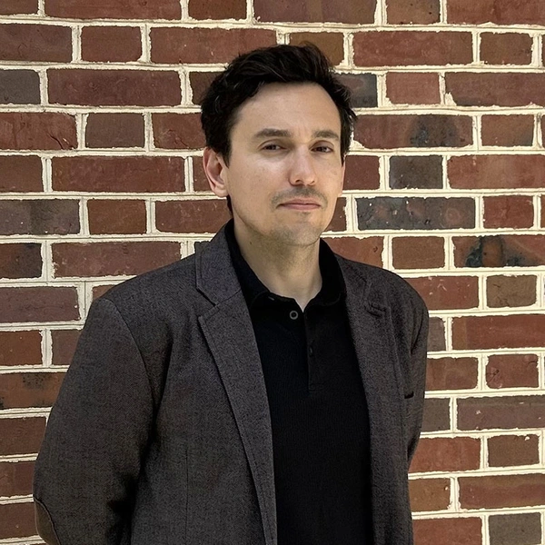 Headshot of Diego Godoy standing in front of a brick wall.