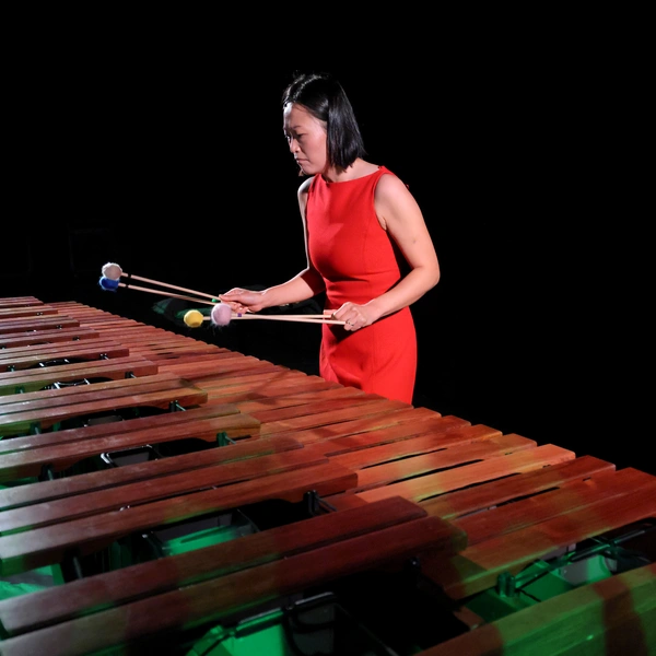 A musician plays xylophone while holding 4 mallets.