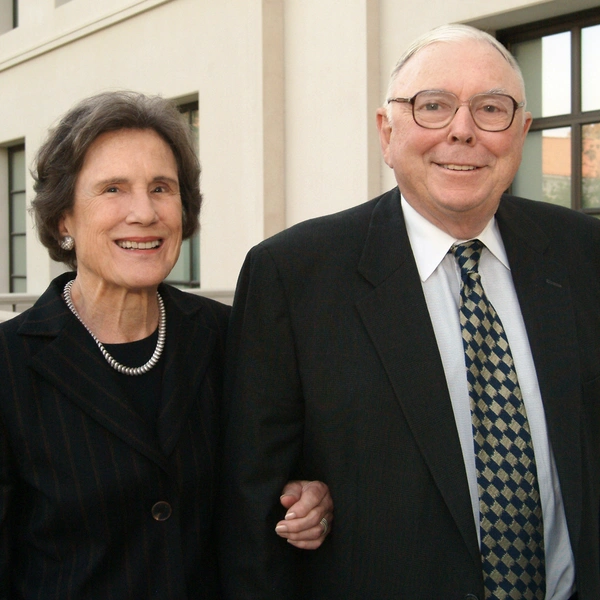 Two people in dark clothing smile at the camera.