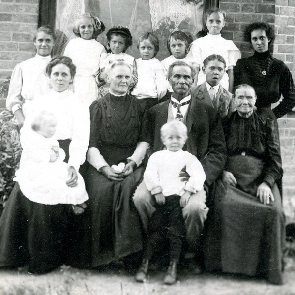 A black and white family portrait taken outdoors in front of a house.