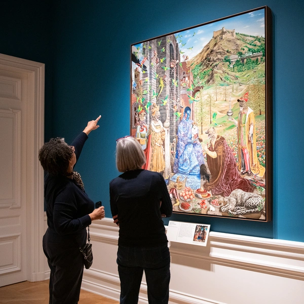 Two people look at a large artwork in a gallery with blue walls.