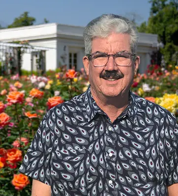 A person stands in a blooming rose garden.