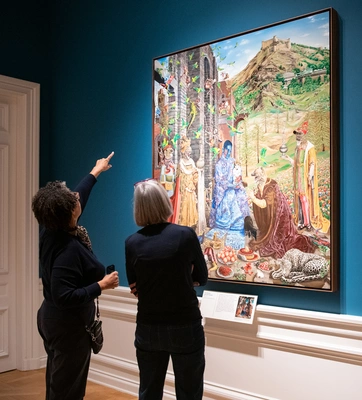 Two people look at a large artwork in a gallery with blue walls.