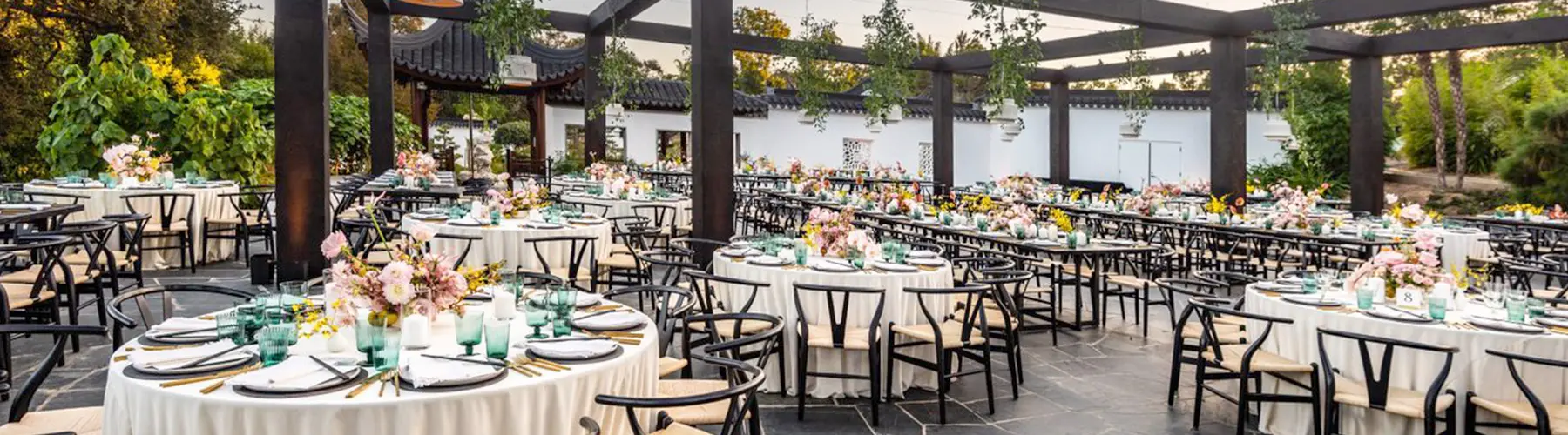 Beautifully adorned tables set up under an open wooden canopy.