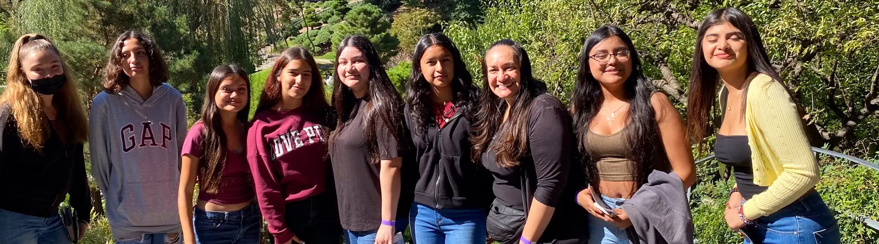 A group of teens pose for a photo in a garden.