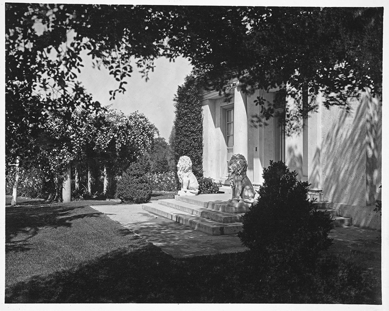 View of the south entrance to the bowling alley (now the tea room), flanked on either side by a stone lion statue, circa 1918.