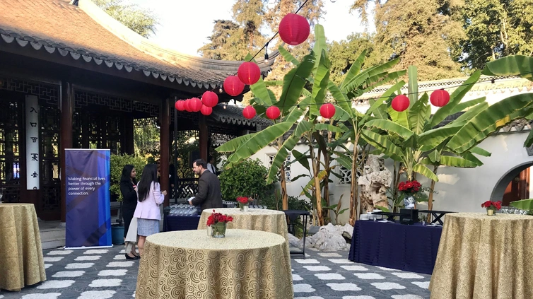 Small cocktail tables covered in gold tablecloths accented overhead by strings of red globe lights.