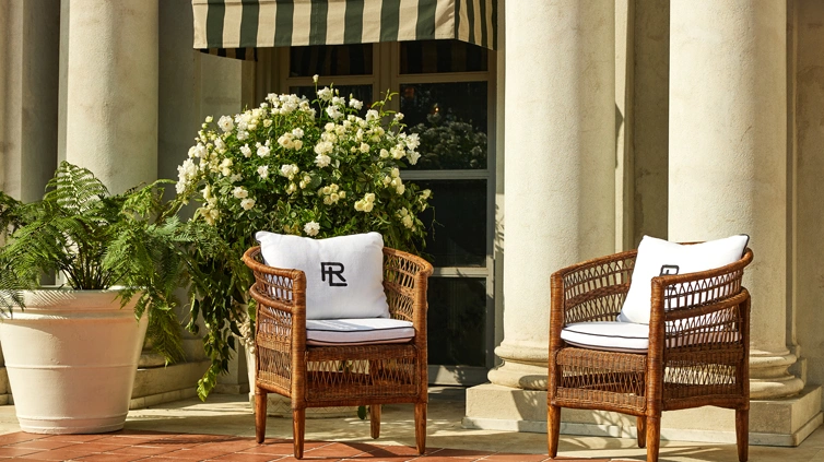 Two candybar brown wicker chairs accented with white back pillows and cushions.