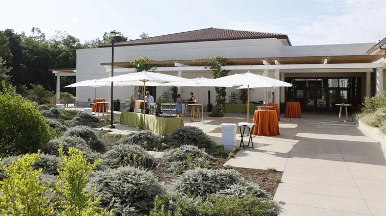 Long shot of cocktail tables under sun umbrellas.	