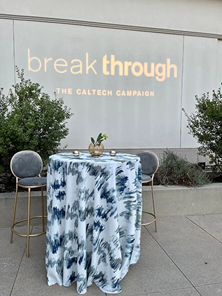 A colorful tablecloth covers a high table.	