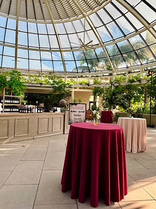 Cocktail high tables with colorful tablecloths set up under a glass dome.