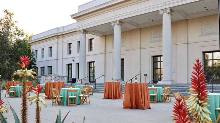 A courtyard filled with party tables covered in teal blue and darker peach tableclothes.