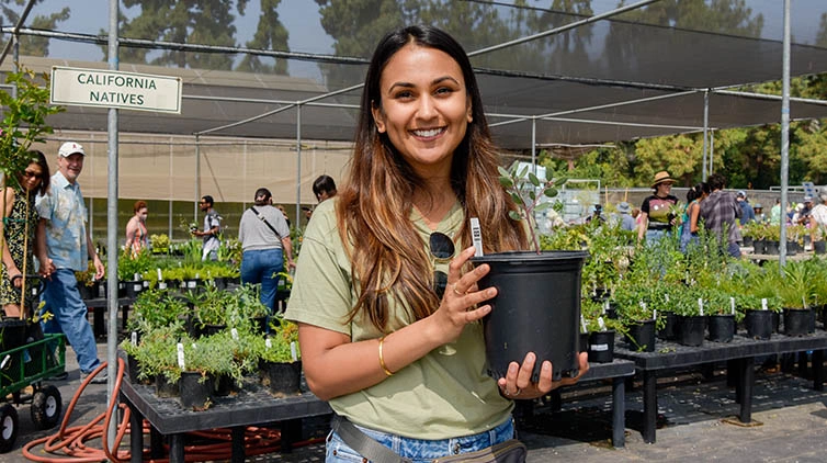 A person holds a small plant and poses for camera.