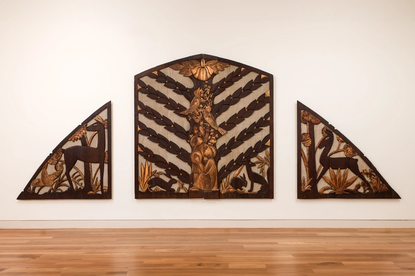 Three carved wood panels on a wall that form a semicircle.