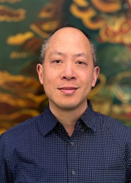 A photograph of a person in a blue collared shirt.