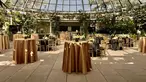 Cocktail tables set up with gold tablecloths under a glass dome.