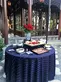 A round event table covered in a deep blue tablecloth is simply adorned with appetizers.