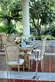 Wooden outdoor dining tables and whicker-backed dining chairs.	