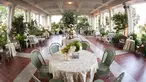 A fish-eye view of a covered outdoor patio with a table and sage-colored whicker chairs in the foreground.	