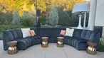 A U-shaped navy blue couch with white and rose pillows.	