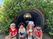 young kids sitting by garden rainbow tunnel