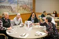 A group of people sit and interact a circular table.