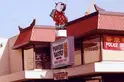 A close-up view of a bakery sign that stands in front of a two-story building.