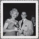 A black-and-white photo of a young man in a suit getting an autograph from Marylin Monroe.