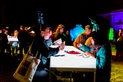 A group of people in costumes sit at a table with lights.